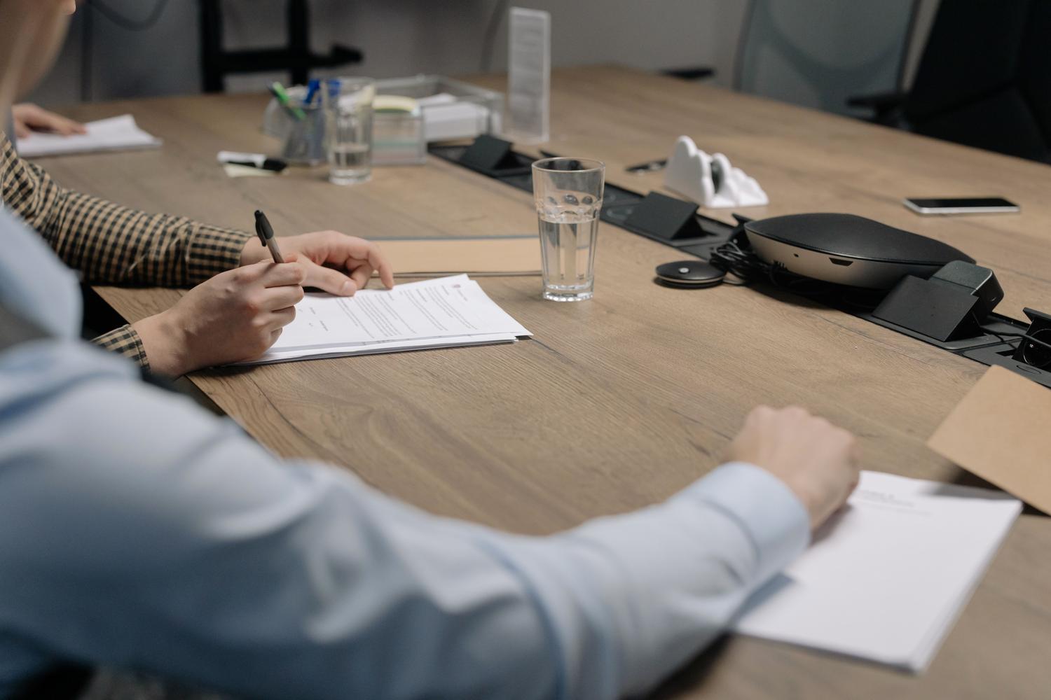 Primer plano de una persona firmando un acuerdo mercantil en una mesa de conferencias Primer plano de una persona firmando un acuerdo mercantil en una mesa de conferencias