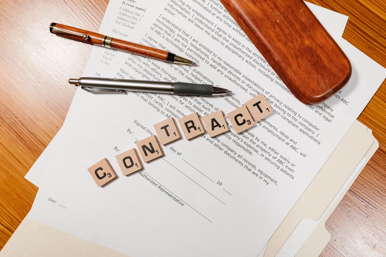 Imagen conceptual con la palabra 'CONTRACT' formada por fichas sobre documentos legales Imagen conceptual con la palabra 'CONTRACT' formada por fichas sobre documentos legales
