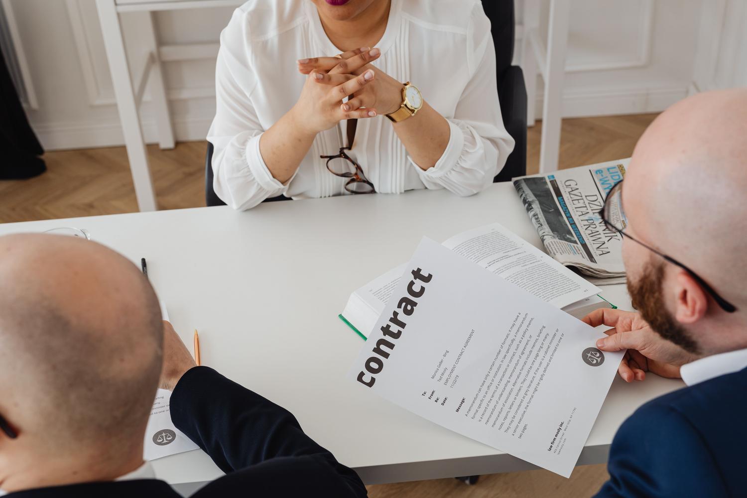 Profesionales revisando los términos de un contrato mercantil en una reunión de negocios Profesionales revisando los términos de un contrato mercantil en una reunión de negocios