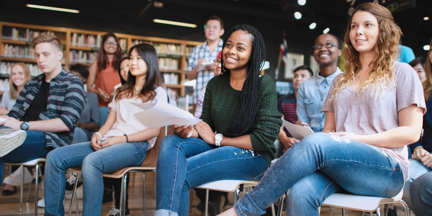 Grupo diverso de jóvenes adultos sonriendo y participando en una clase universitaria en un aula contemporánea. Grupo diverso de jóvenes adultos sonriendo y participando en una clase universitaria en un aula contemporánea.