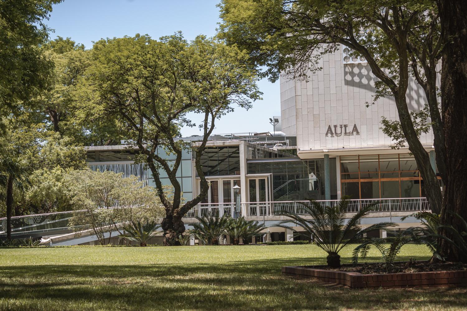 Edificio moderno de una facultad universitaria rodeado de zonas verdes, representando las infraestructuras académicas. Edificio moderno de una facultad universitaria rodeado de zonas verdes, representando las infraestructuras académicas.