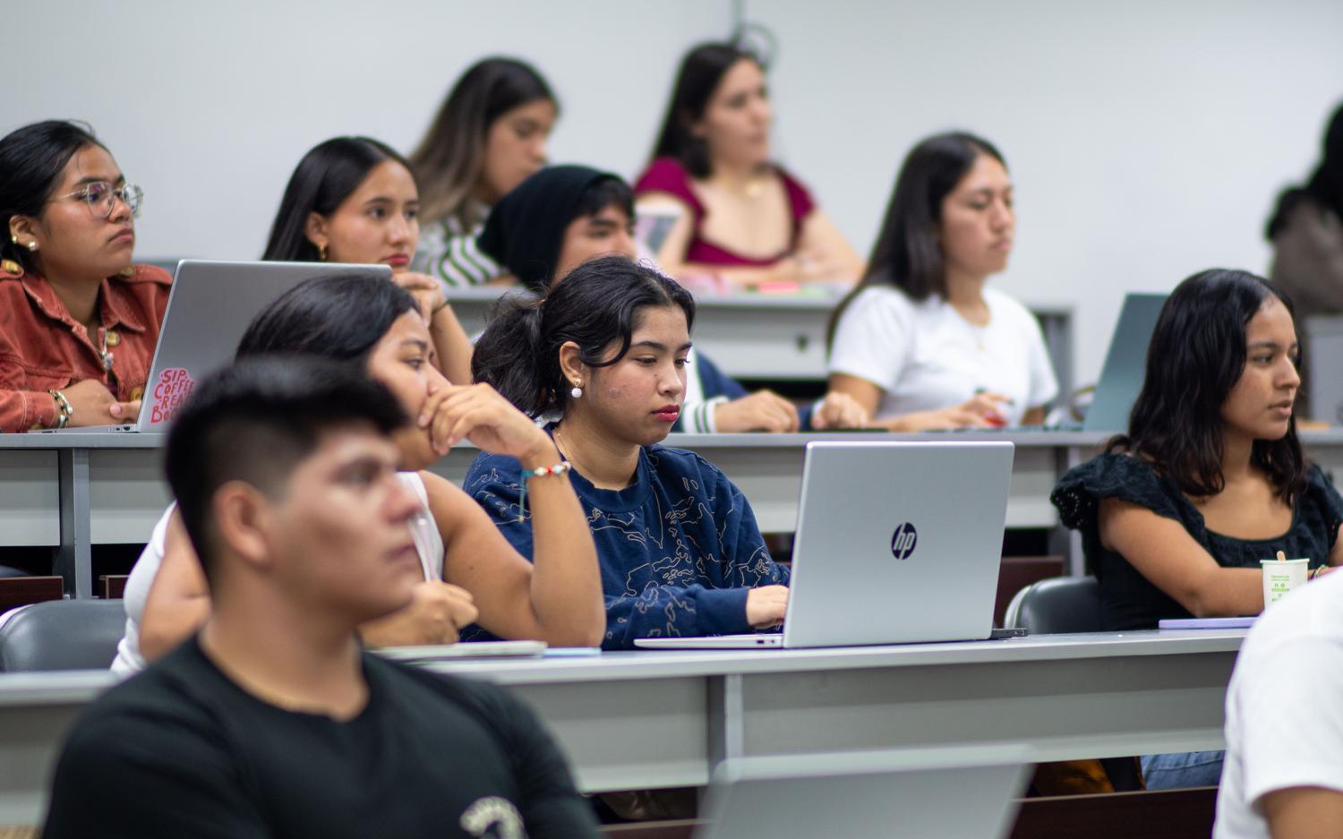 Grupo diverso de estudiantes universitarios atendiendo a una clase magistral en el aula de la facultad. Grupo diverso de estudiantes universitarios atendiendo a una clase magistral en el aula de la facultad.