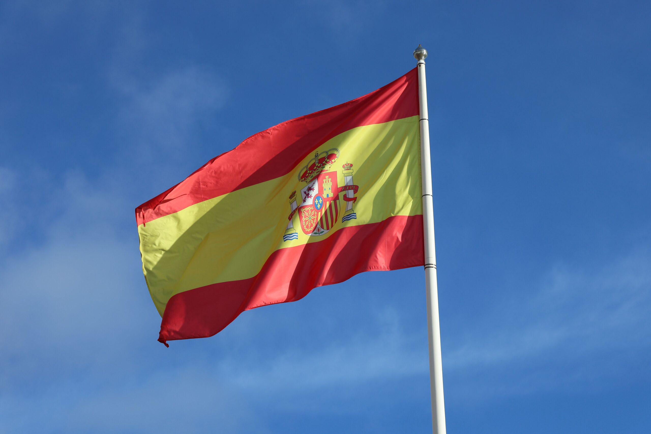 Bandera de España ondeando contra un cielo azul, representando la identidad y el sentido de pertenencia a la patria. Bandera de España ondeando contra un cielo azul, representando la identidad y el sentido de pertenencia a la patria.