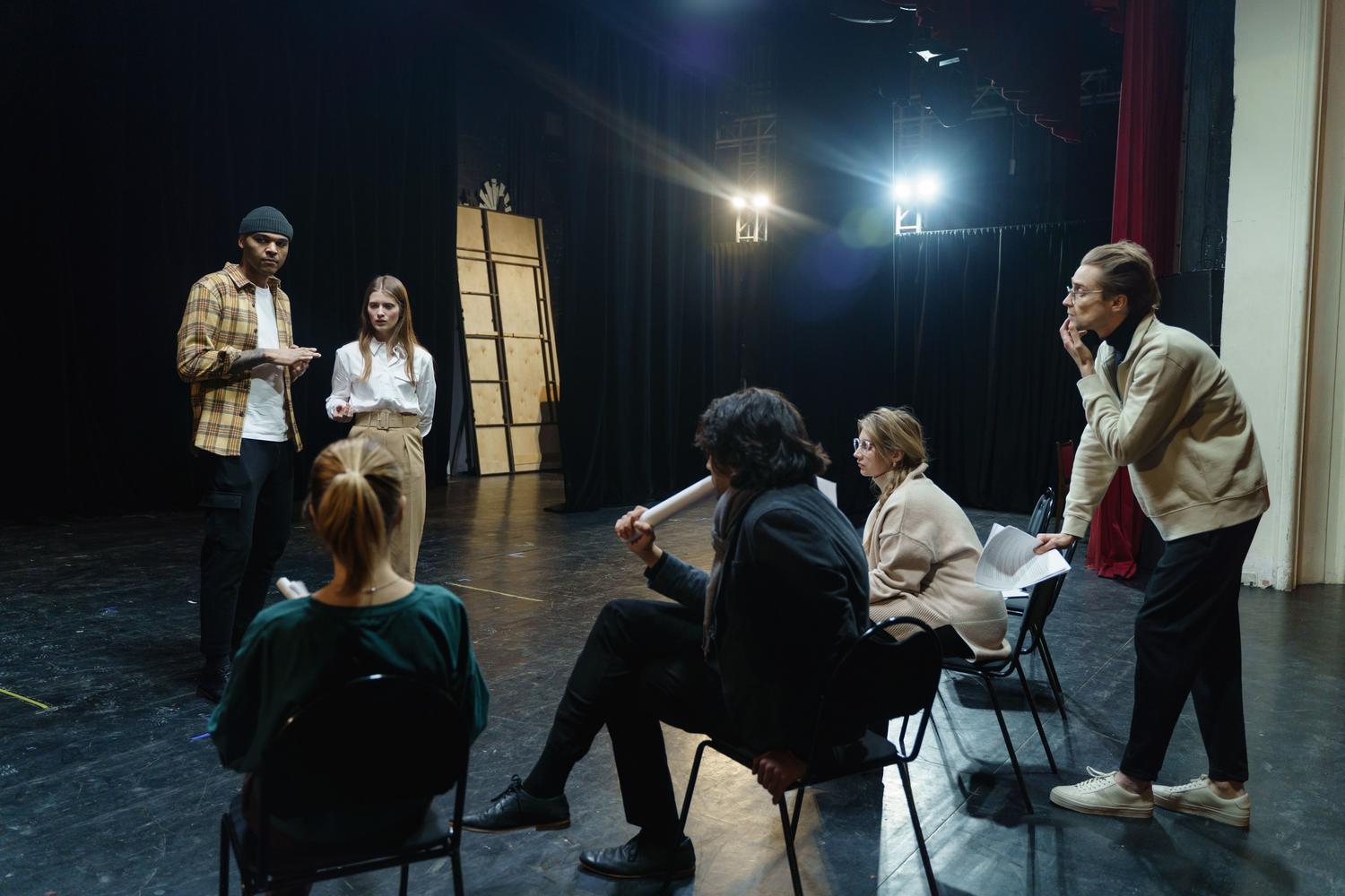 Actores ensayando una escena en un escenario de teatro con la guía de un director, representando las artes escénicas. Actores ensayando una escena en un escenario de teatro con la guía de un director, representando las artes escénicas.