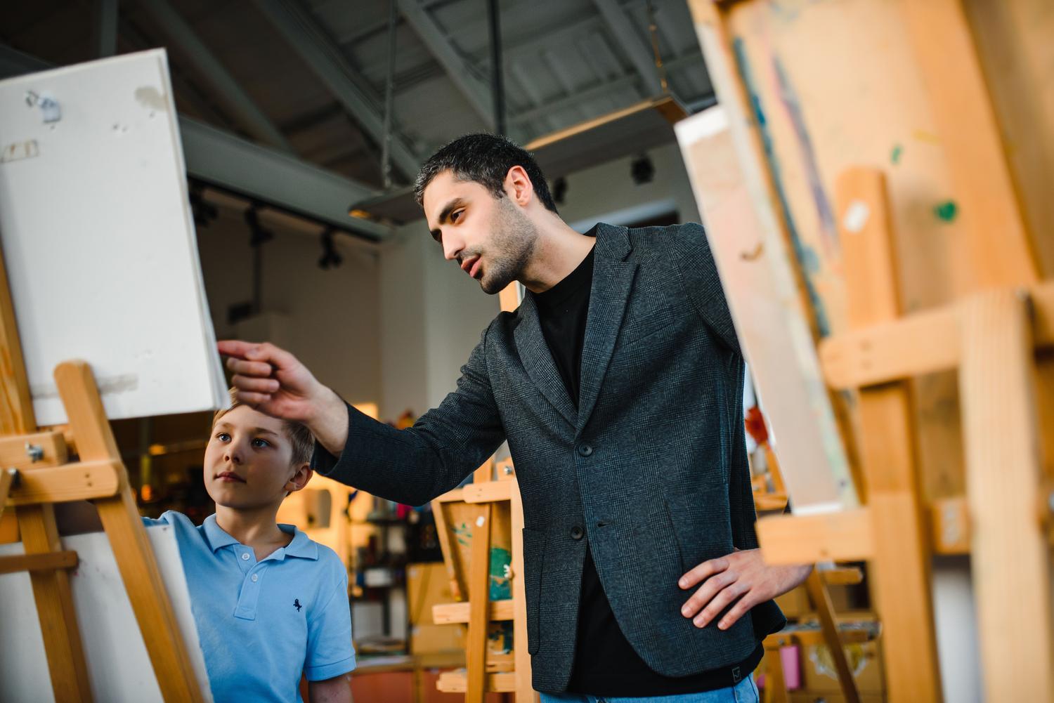 Profesor de artes plásticas instruyendo a un alumno en un estudio de pintura, representando la docencia artística. Profesor de artes plásticas instruyendo a un alumno en un estudio de pintura, representando la docencia artística.