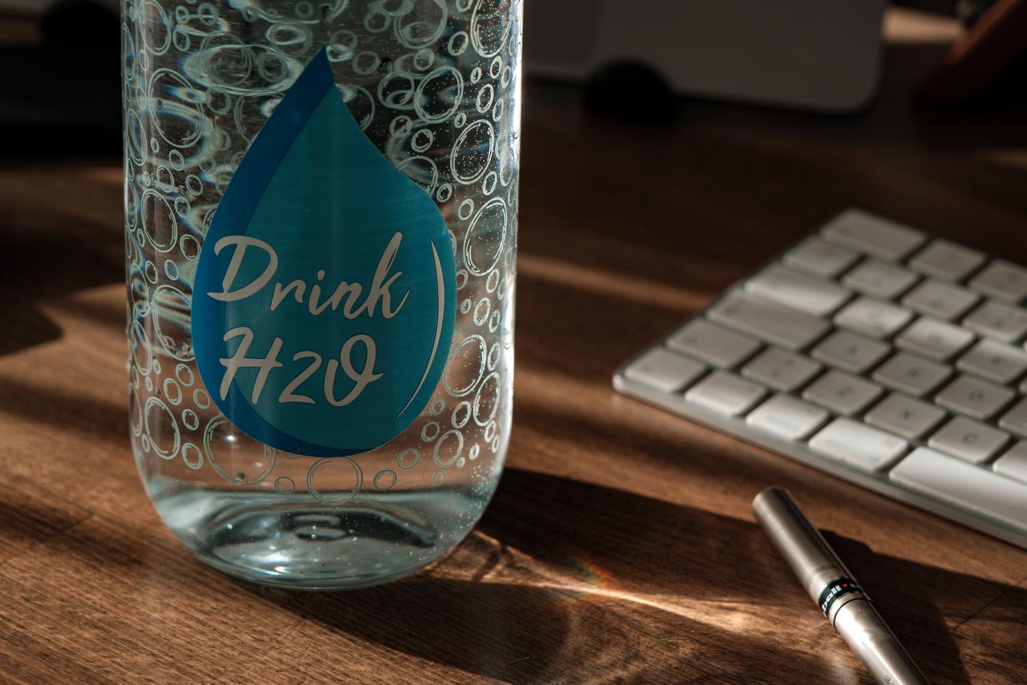 Botella de agua sobre un escritorio de oficina, resaltando la importancia de la hidratación constante. Botella de agua sobre un escritorio de oficina, resaltando la importancia de la hidratación constante.