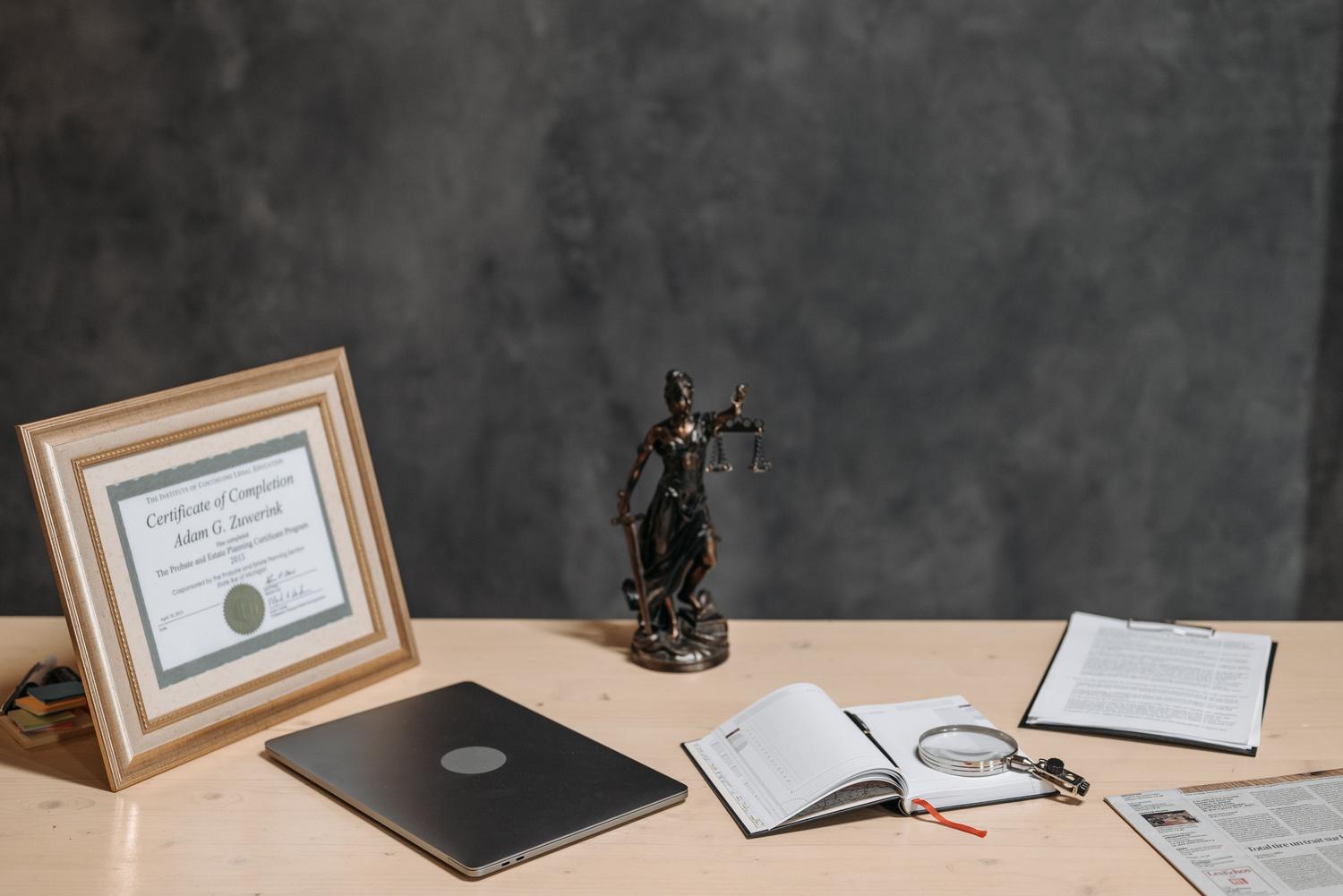 Escritorio de abogado con una estatua de la justicia, lupa y documentos, ilustrando el análisis y la interpretación jurídica. Escritorio de abogado con una estatua de la justicia, lupa y documentos, ilustrando el análisis y la interpretación jurídica.