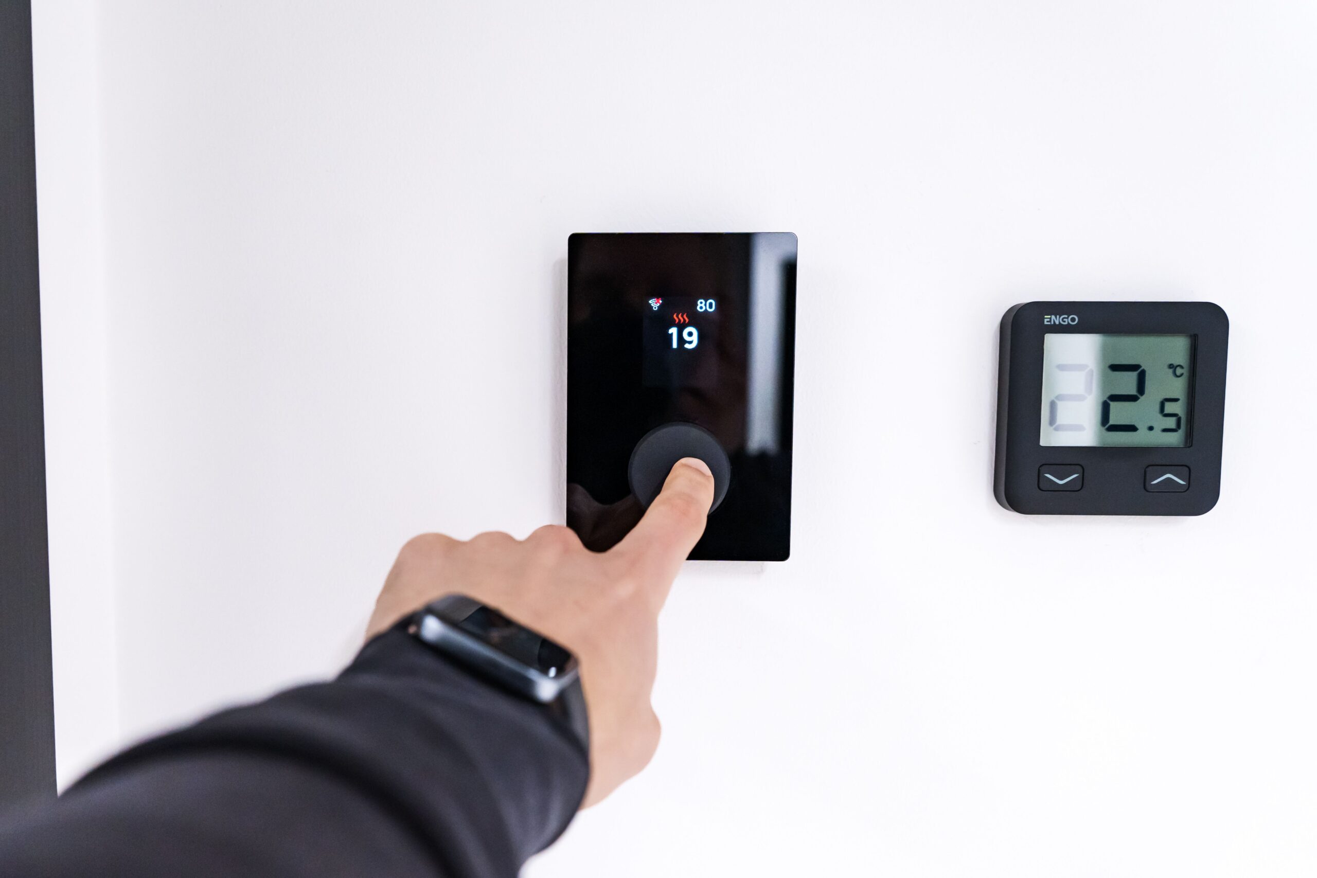 Mano ajustando un termostato digital inteligente en un hogar moderno, representando la capacidad de la IA para reducir el desperdicio energético cotidiano. Mano ajustando un termostato digital inteligente en un hogar moderno, representando la capacidad de la IA para reducir el desperdicio energético cotidiano.