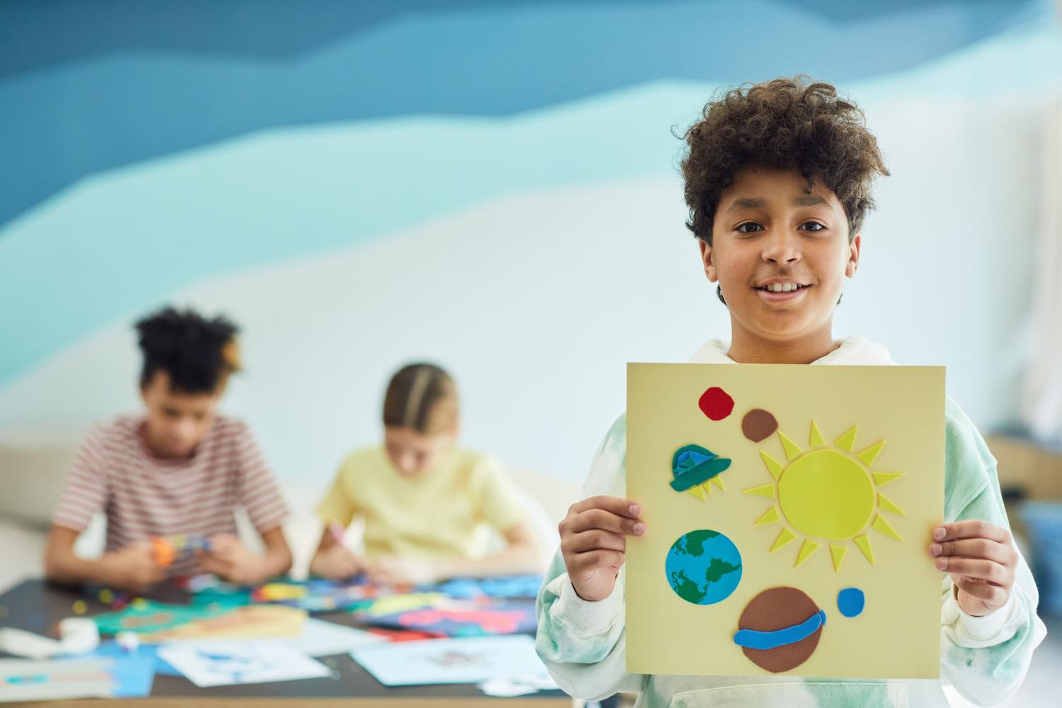 Niño mostrando un proyecto escolar sobre el sistema solar en un aula Niño mostrando un proyecto escolar sobre el sistema solar en un aula