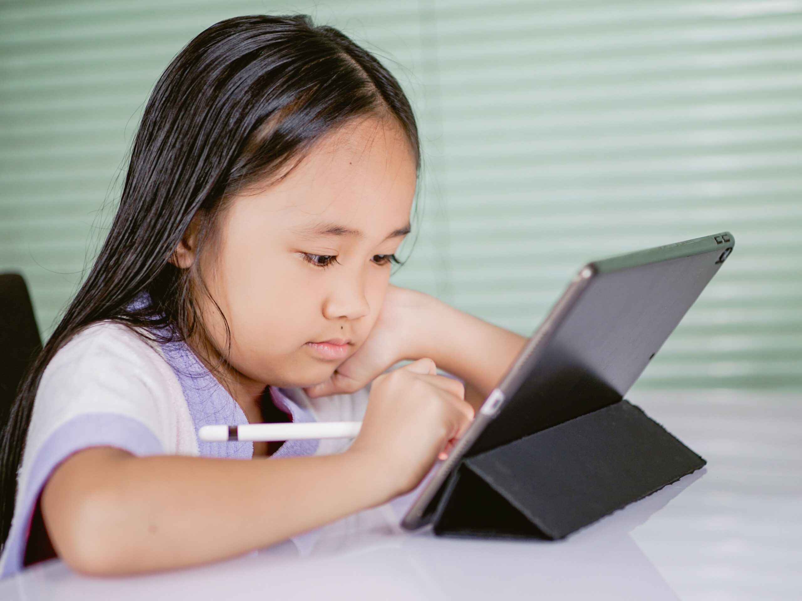 Niña utilizando una tablet y un lápiz digital para interactuar con contenidos educativos en una plataforma virtual. Niña utilizando una tablet y un lápiz digital para interactuar con contenidos educativos en una plataforma virtual.
