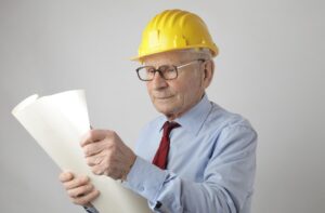 Ingeniero senior con casco y planos, representando la experiencia y la actividad laboral prolongada.