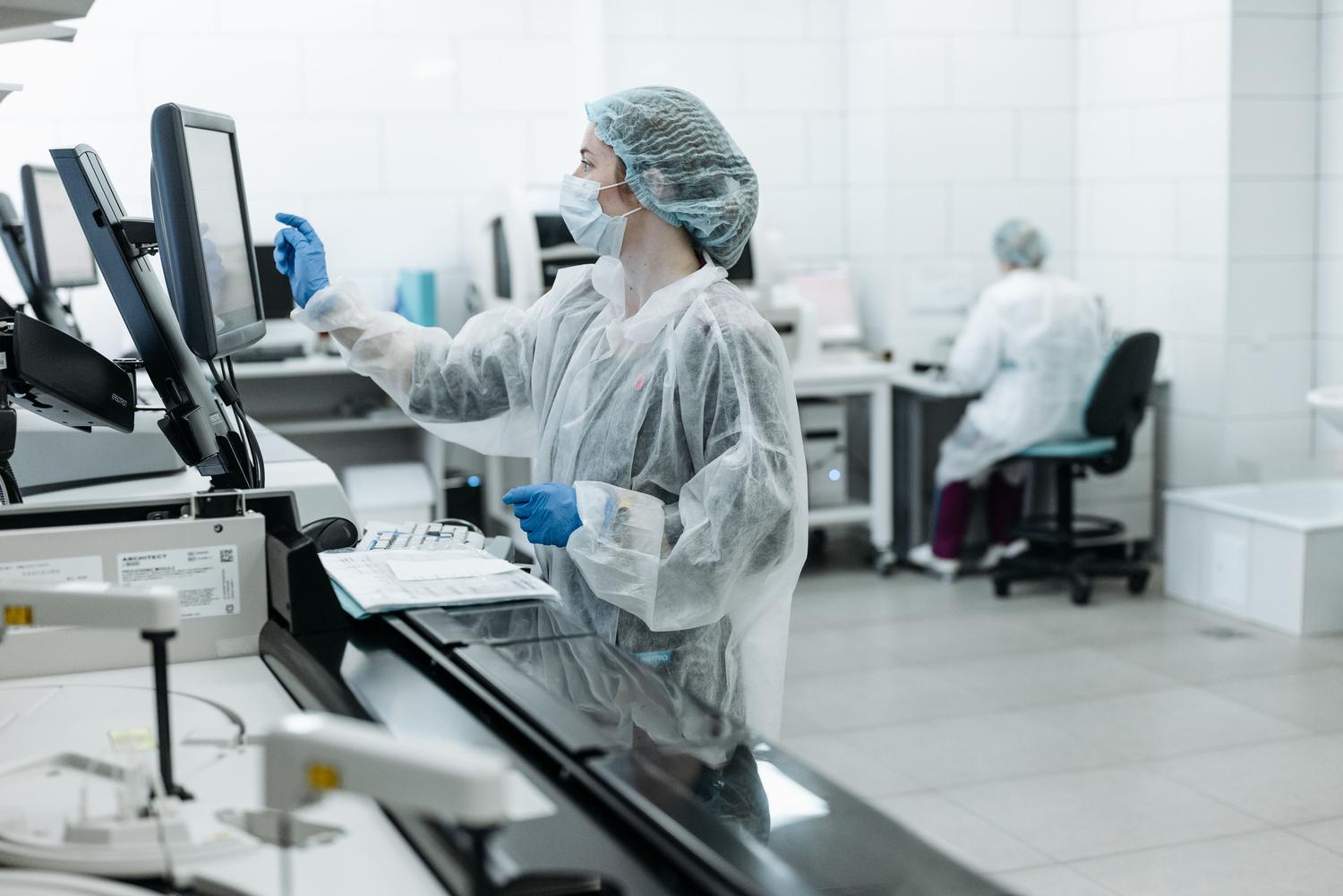 Técnica de laboratorio analizando datos complejos en un ordenador junto a maquinaria de análisis genómico. Técnica de laboratorio analizando datos complejos en un ordenador junto a maquinaria de análisis genómico.