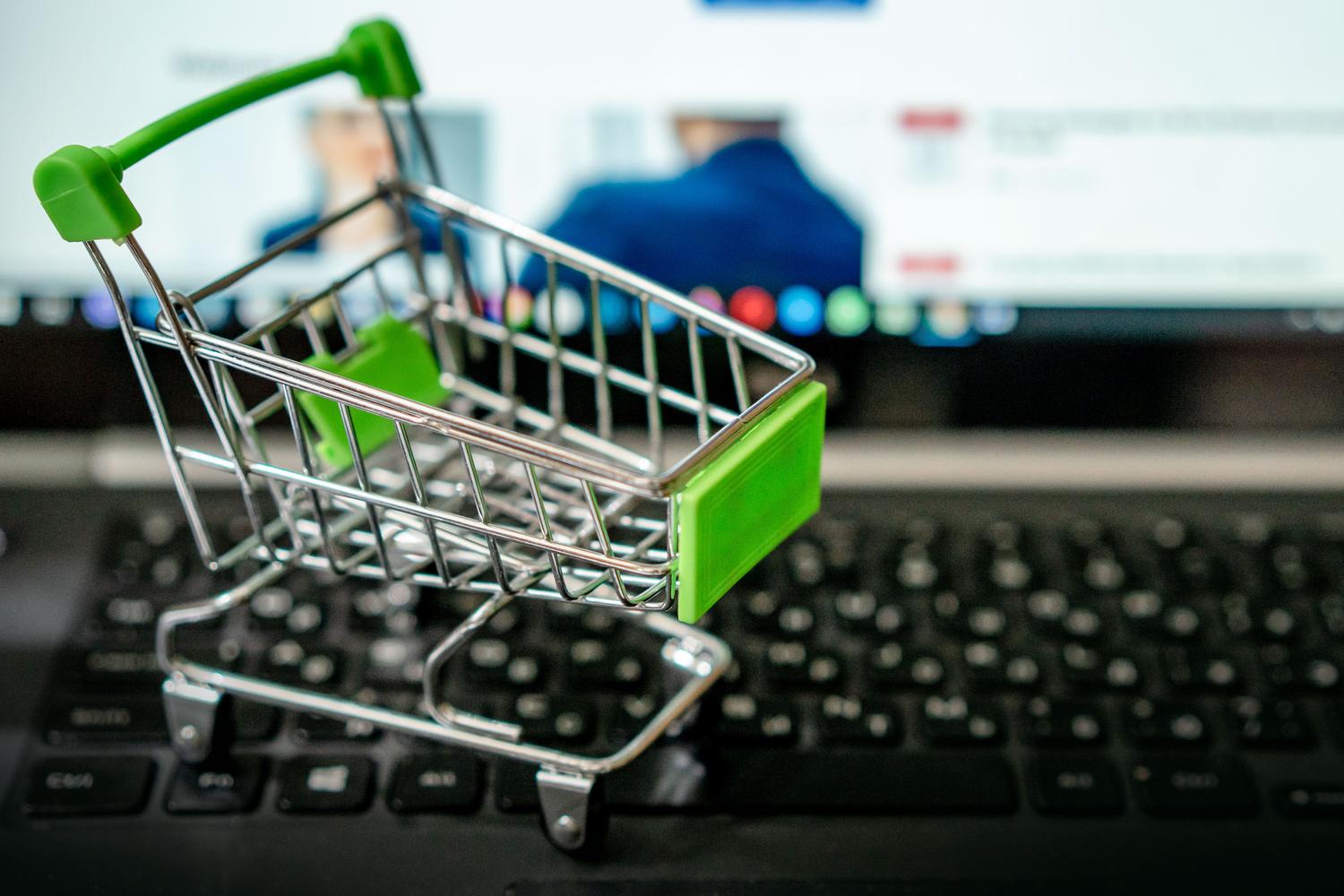 Comercio electrónico y ventas online Un carrito de compras en miniatura sobre el teclado de un ordenador portátil, simbolizando el comercio electrónico y las ventas online.