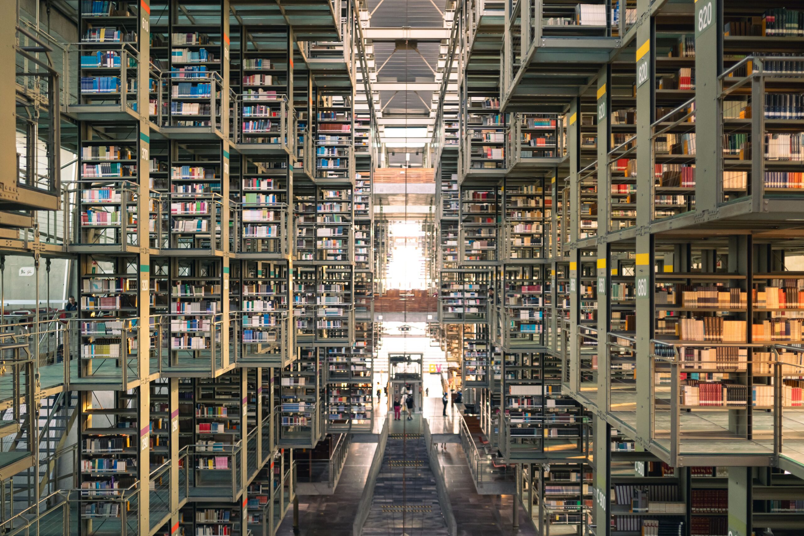Interior de una biblioteca moderna con amplias estanterías de libros, representando el entorno de investigación académica Interior de una biblioteca moderna con amplias estanterías de libros, representando el entorno de investigación académica