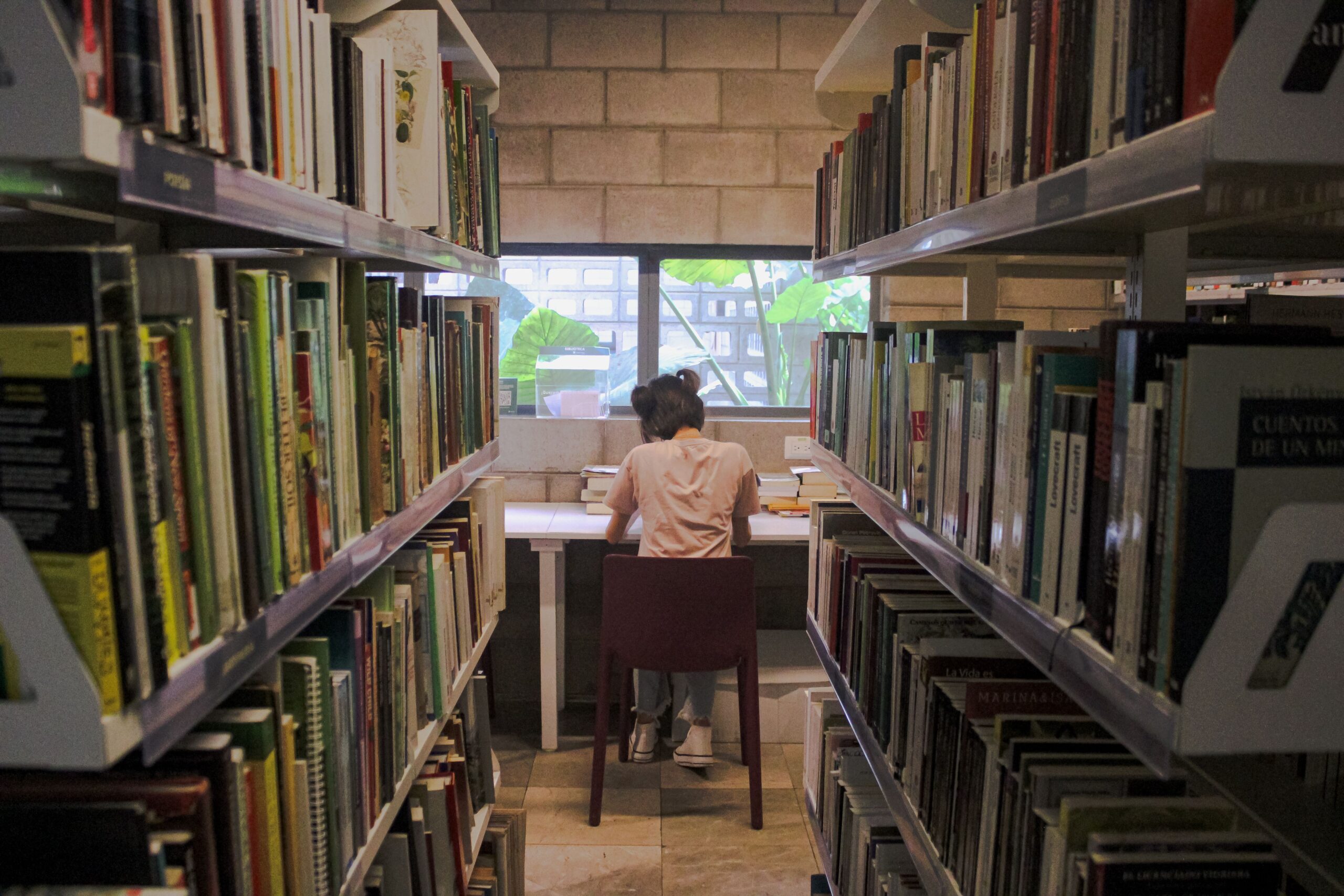 Estudiante concentrado leyendo libros en una biblioteca universitaria Estudiante concentrado leyendo libros en una biblioteca universitaria