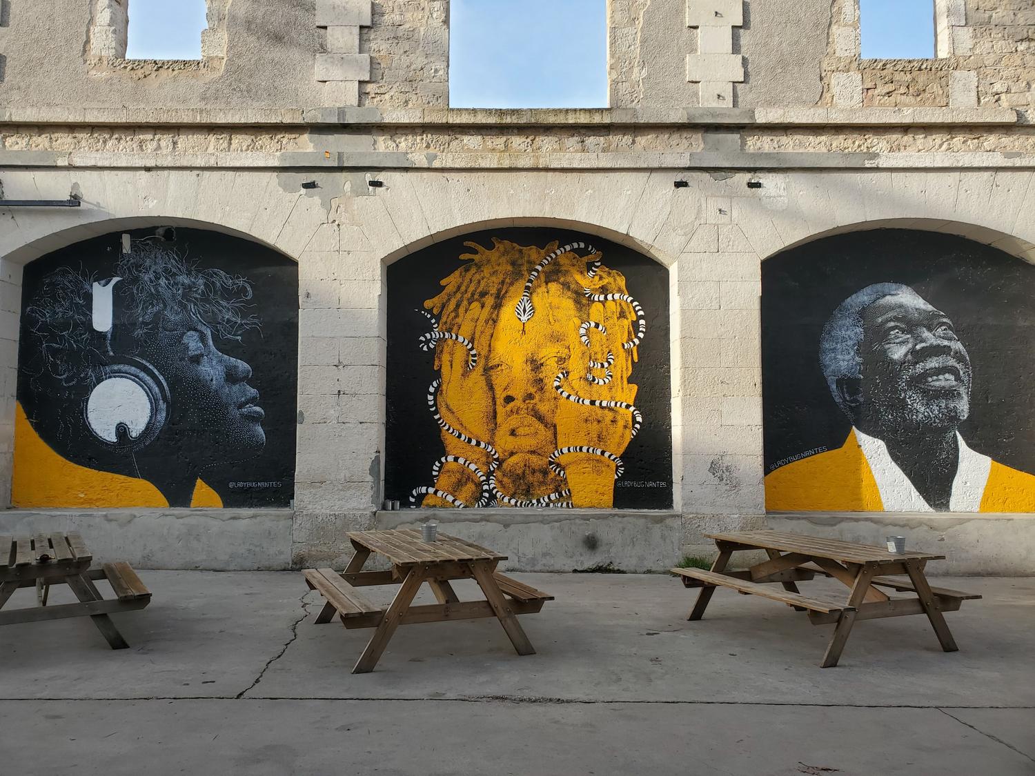 Espacio público embellecido con murales y mesas de madera, fomentando la interacción comunitaria a través del arte. Espacio público embellecido con murales y mesas de madera, fomentando la interacción comunitaria a través del arte.