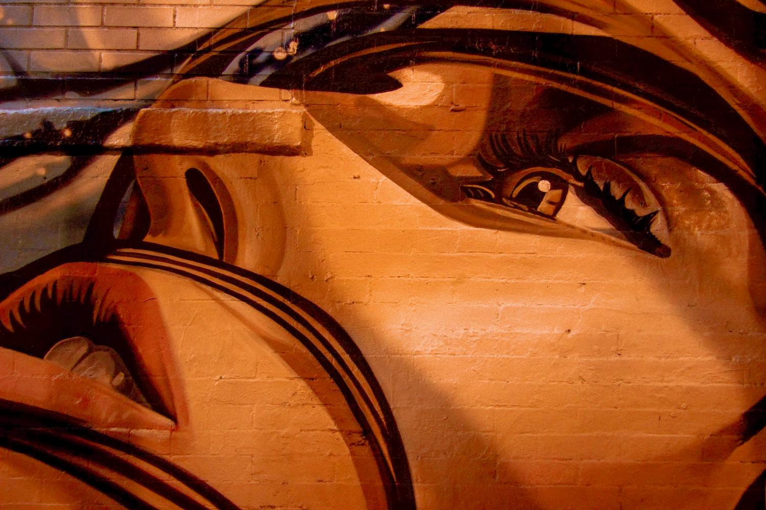 Primer plano de un mural detallado de un rostro humano sobre una pared de ladrillos urbanos. Primer plano de un mural detallado de un rostro humano sobre una pared de ladrillos urbanos.