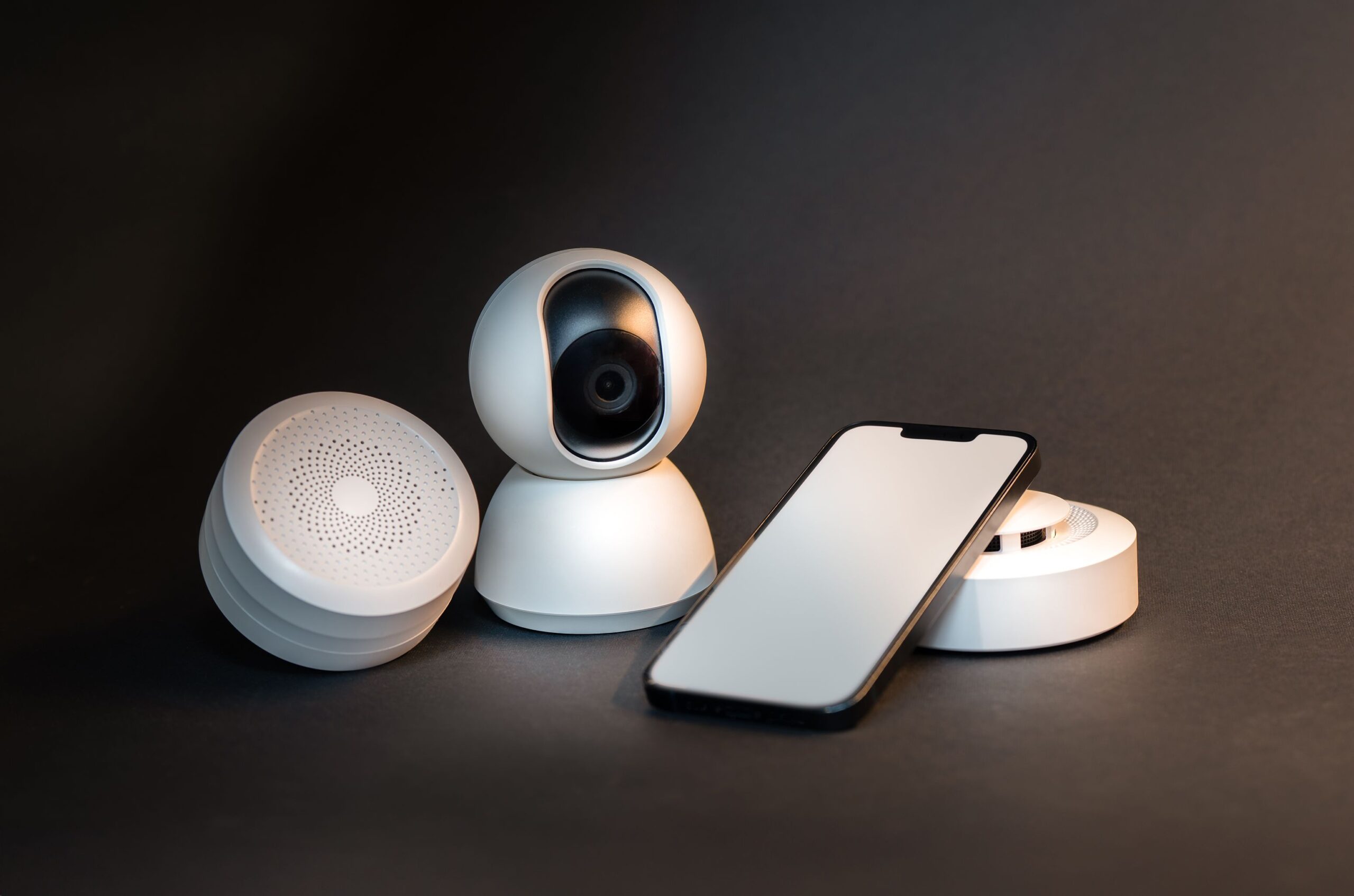 Dispositivos de hogar inteligente y un smartphone organizados minimalistamente, representando la datificación del entorno doméstico. Dispositivos de hogar inteligente y un smartphone organizados minimalistamente, representando la datificación del entorno doméstico.
