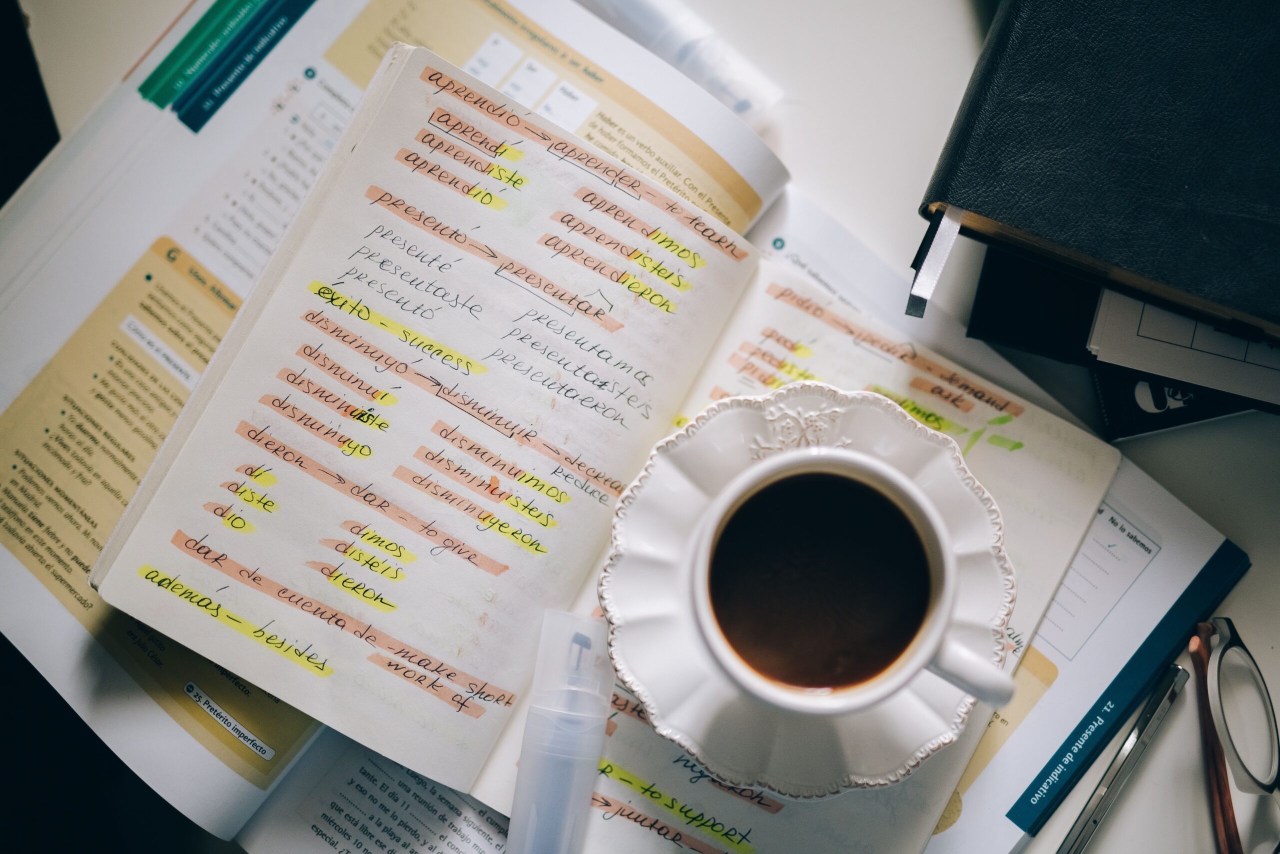 Cuaderno de apuntes en español con ejercicios de verbos y una taza de café, representando el estudio activo del idioma. Cuaderno de apuntes en español con ejercicios de verbos y una taza de café, representando el estudio activo del idioma.
