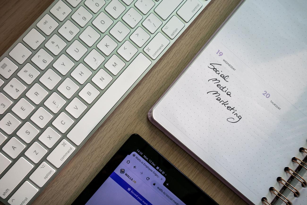 Vista superior de un teclado y una agenda con notas de marketing en redes sociales, ideal para la sección de moderación de contenidos. Vista superior de un teclado y una agenda con notas de marketing en redes sociales, ideal para la sección de moderación de contenidos.