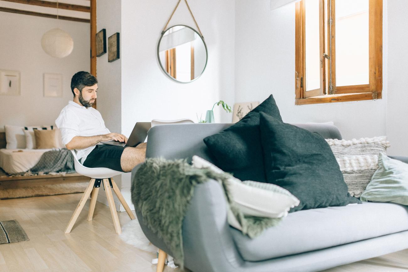Hombre trabajando con un portátil en un salón moderno y luminoso, representando la flexibilidad del teletrabajo. Hombre trabajando con un portátil en un salón moderno y luminoso, representando la flexibilidad del teletrabajo.