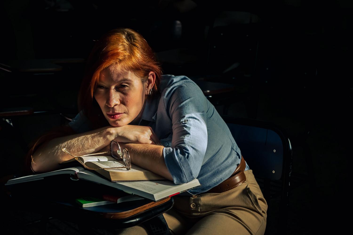 Estudiante cansada con mirada perdida apoyada en su pupitre, representando el vacío motivacional en la educación Estudiante cansada con mirada perdida apoyada en su pupitre, representando el vacío motivacional en la educación