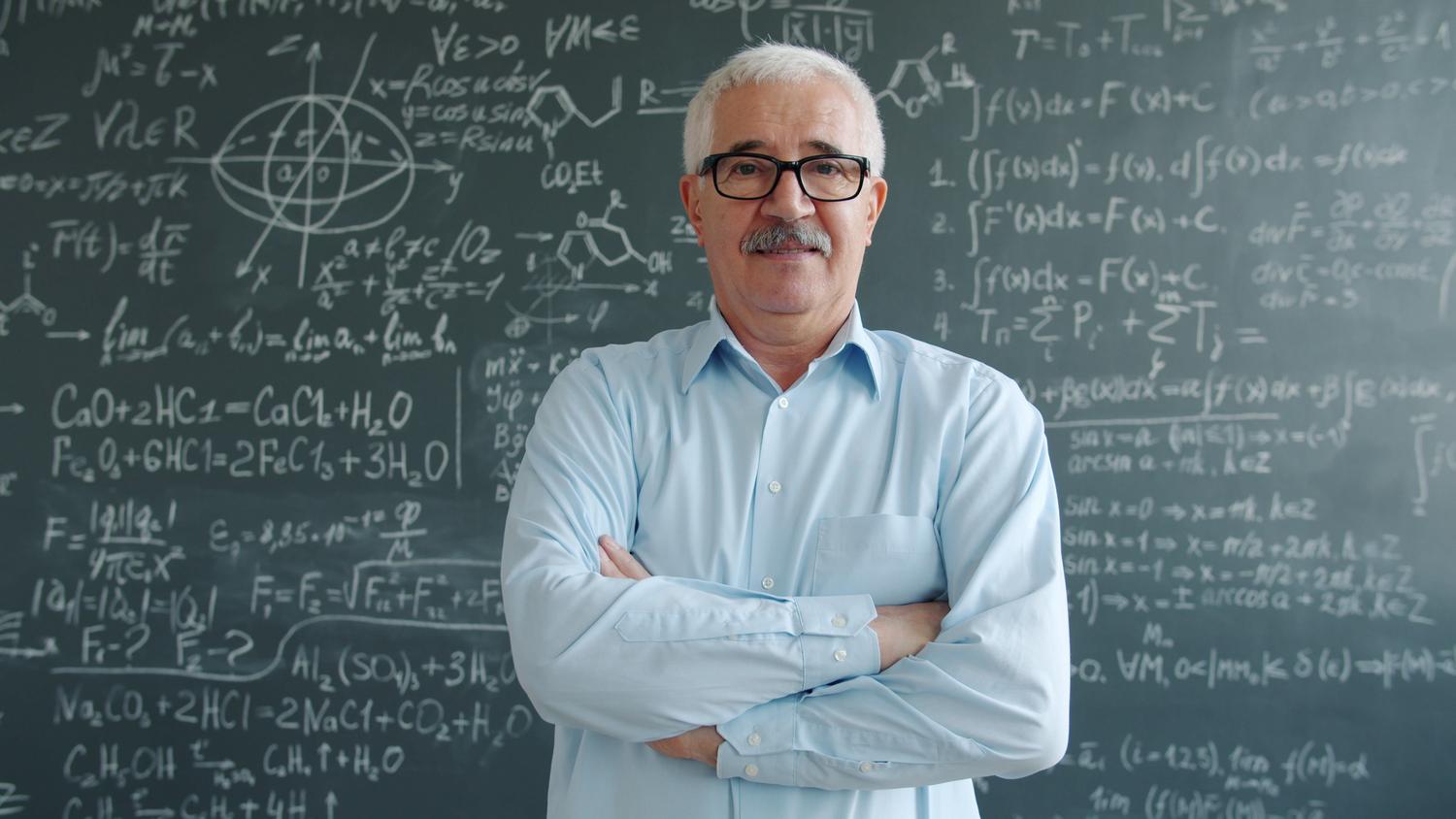 Profesor veterano frente a una pizarra con ecuaciones científicas, representando la culminación de la carrera académica como Catedrático. Profesor veterano frente a una pizarra con ecuaciones científicas, representando la culminación de la carrera académica como Catedrático.
