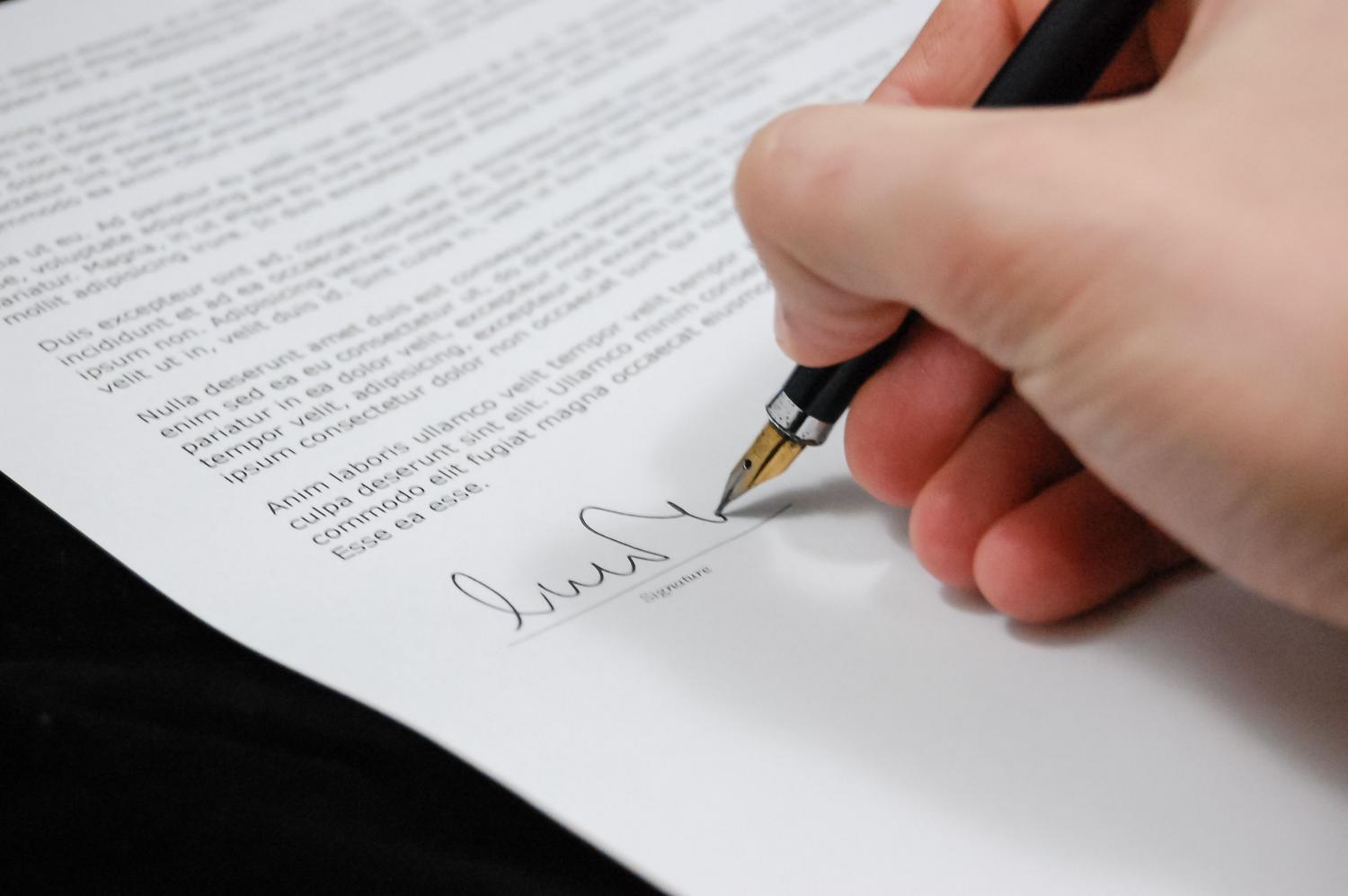 Primer plano de una mano firmando un documento oficial, ilustrando los procesos burocráticos y de acreditación. Primer plano de una mano firmando un documento oficial, ilustrando los procesos burocráticos y de acreditación.