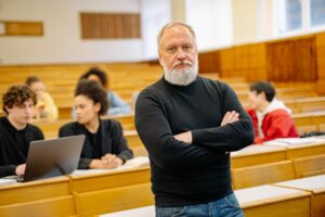 Profesor universitario dando clase en un aula magna con estudiantes, representando el prestigio y la carrera docente.
