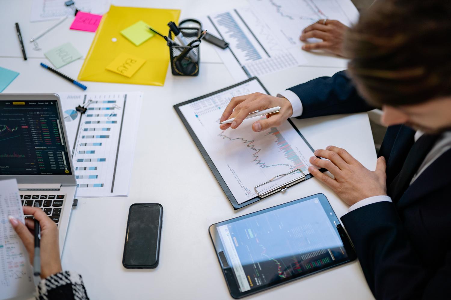 Equipo de analistas financieros colaborando y revisando reportes de riesgo en tablets. Equipo de analistas financieros colaborando y revisando reportes de riesgo en tablets.