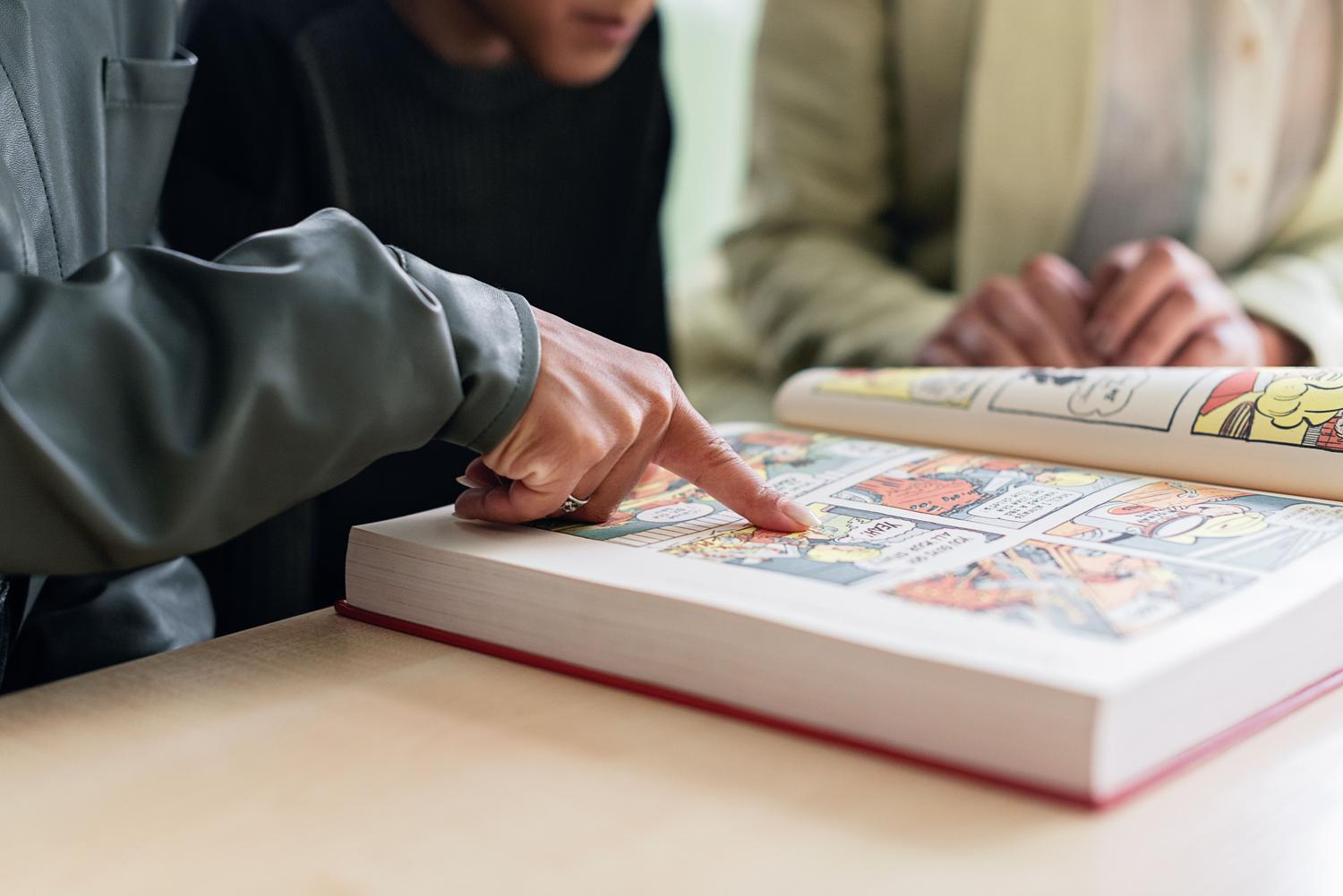 Personas analizando un cómic en un entorno educativo, ilustrando el uso de la novela gráfica como herramienta didáctica universitaria. Personas analizando un cómic en un entorno educativo, ilustrando el uso de la novela gráfica como herramienta didáctica universitaria.