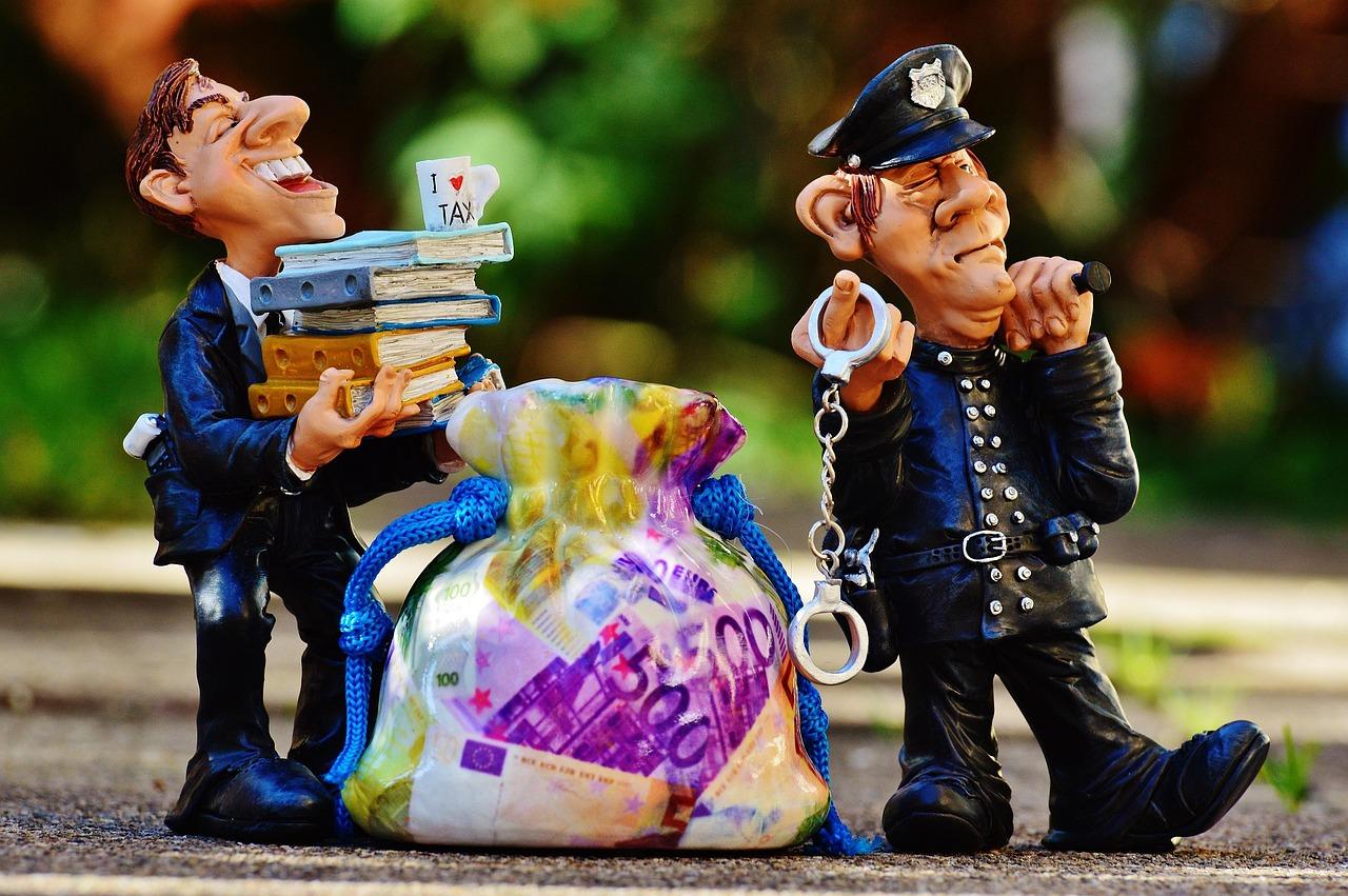Esposas sobre formularios de impuestos y dinero, representando el delito fiscal y el fraude. Esposas sobre formularios de impuestos y dinero, representando el delito fiscal y el fraude.