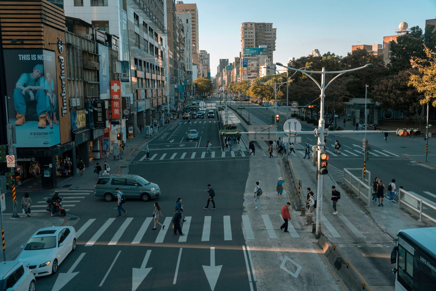 Cruce peatonal concurrido en una ciudad moderna Cruce peatonal concurrido en una ciudad moderna, representando la Teoría de la Actividad Rutinaria y la creación de flujos de oportunidad delictiva.