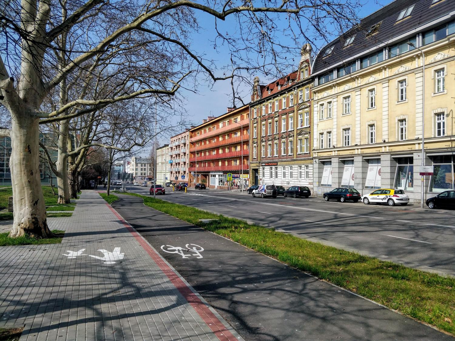 Calle europea limpia y bien mantenida con carriles bici y arquitectura abierta Calle europea limpia y bien mantenida con carriles bici y arquitectura abierta, ejemplificando los principios de vigilancia natural y mantenimiento del modelo CPTED.