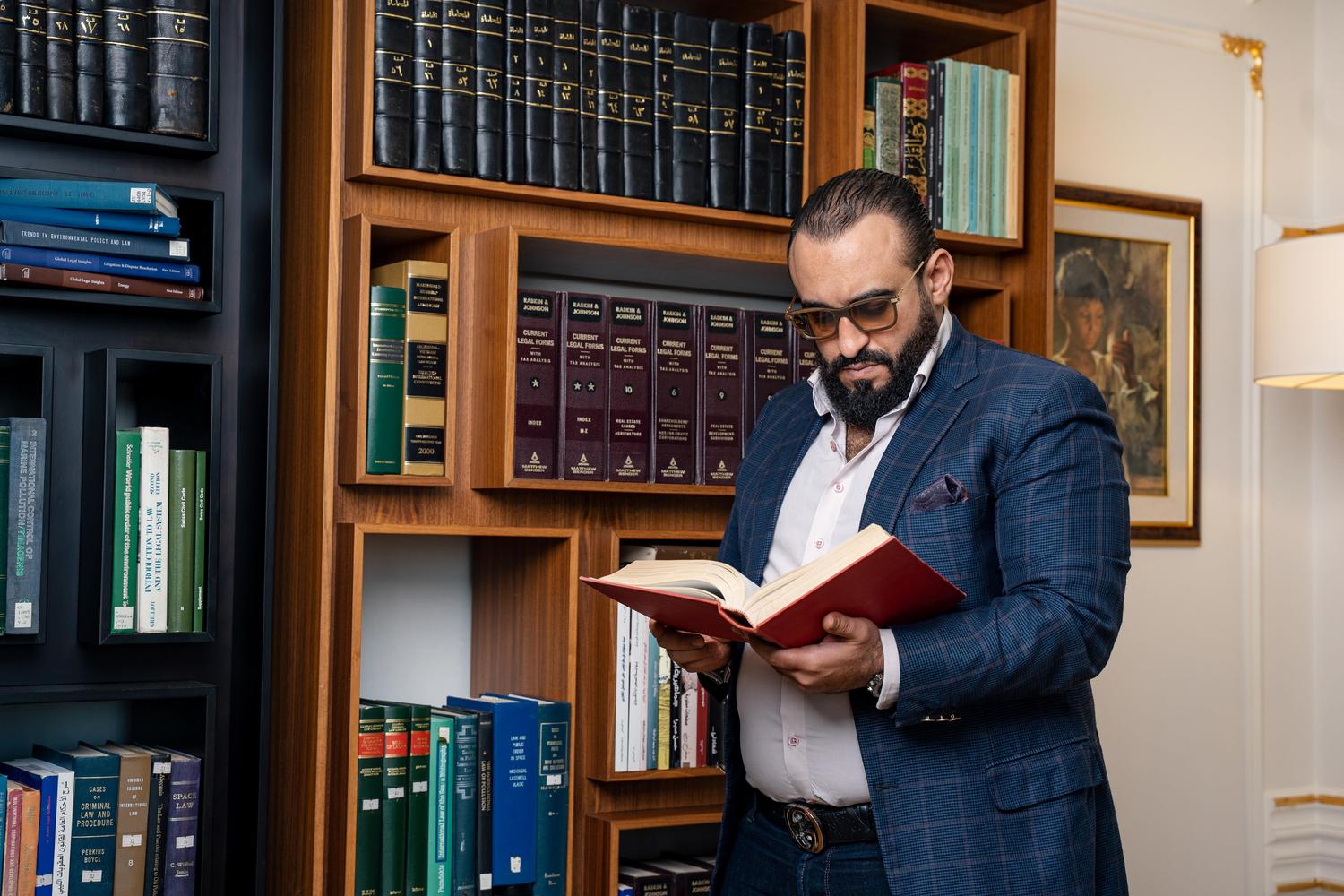 Hombre con gafas leyendo en una biblioteca clásica, simbolizando el rigor científico y la inmersión en el conocimiento requerida para un doctorado. Hombre con gafas leyendo en una biblioteca clásica, simbolizando el rigor científico y la inmersión en el conocimiento requerida para un doctorado.