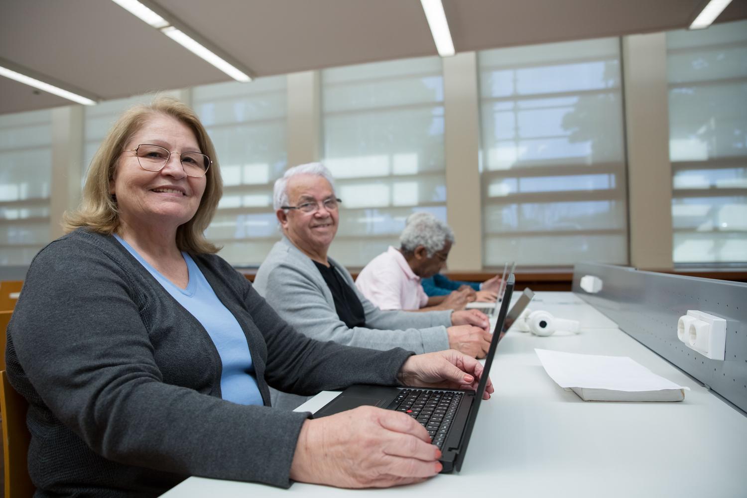 Lifelong learning seniors Seniors learning computer skills in a modern classroom setting, illustrating the importance of digital literacy and upskilling in lifelong learning.