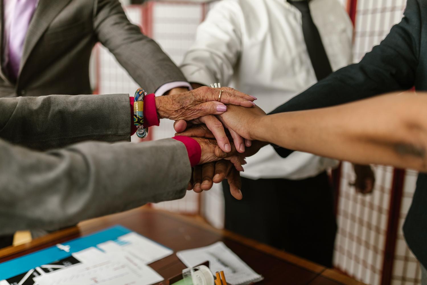 Equipo en sinergia Grupo diverso de profesionales uniendo sus manos en señal de equipo y sinergia para un proyecto conjunto.