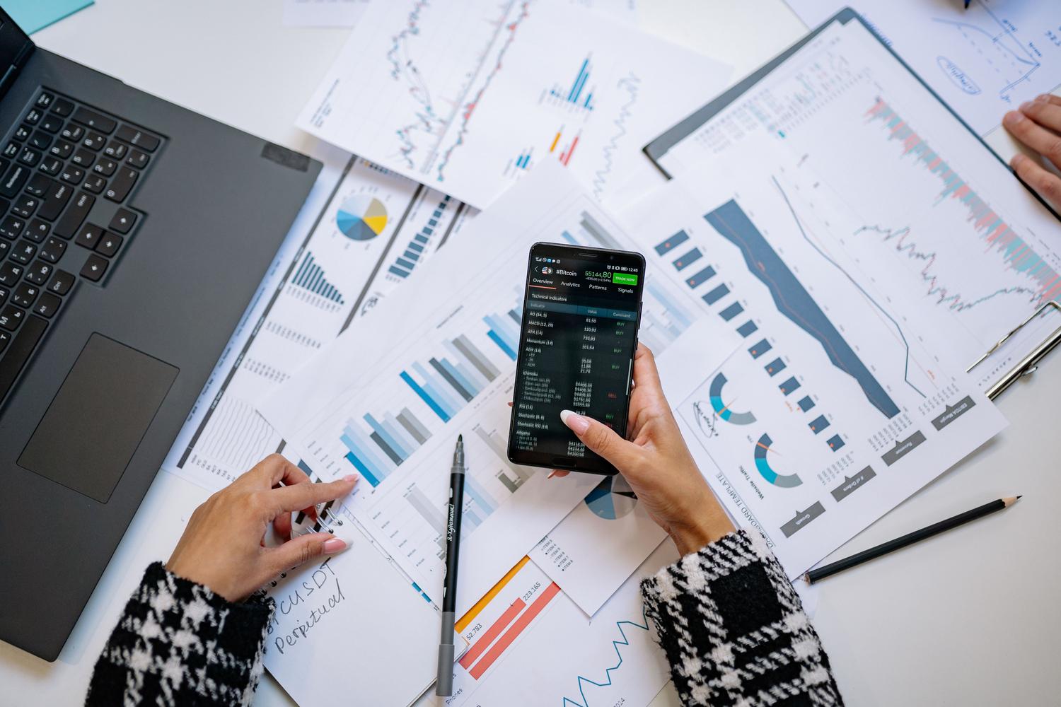 Vista cenital de gráficos financieros y smartphone en una oficina, simbolizando el análisis de datos y el pensamiento analítico. Vista cenital de gráficos financieros y smartphone en una oficina, simbolizando el análisis de datos y el pensamiento analítico.