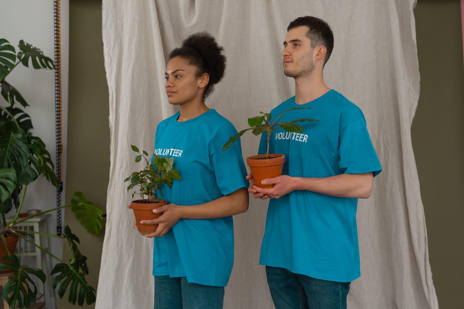 Dos jóvenes voluntarios sosteniendo plantas jóvenes en macetas, simbolizando el compromiso ambiental y la sostenibilidad empresarial. Dos jóvenes voluntarios sosteniendo plantas jóvenes en macetas, simbolizando el compromiso ambiental y la sostenibilidad empresarial.