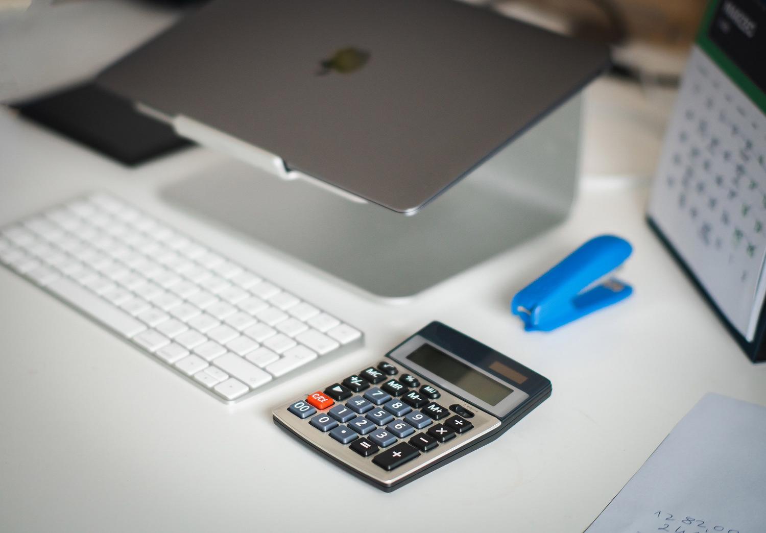 Escritorio organizado con portátil y calculadora, simbolizando la planificación financiera y contable. Escritorio organizado con portátil y calculadora, simbolizando la planificación financiera y contable.