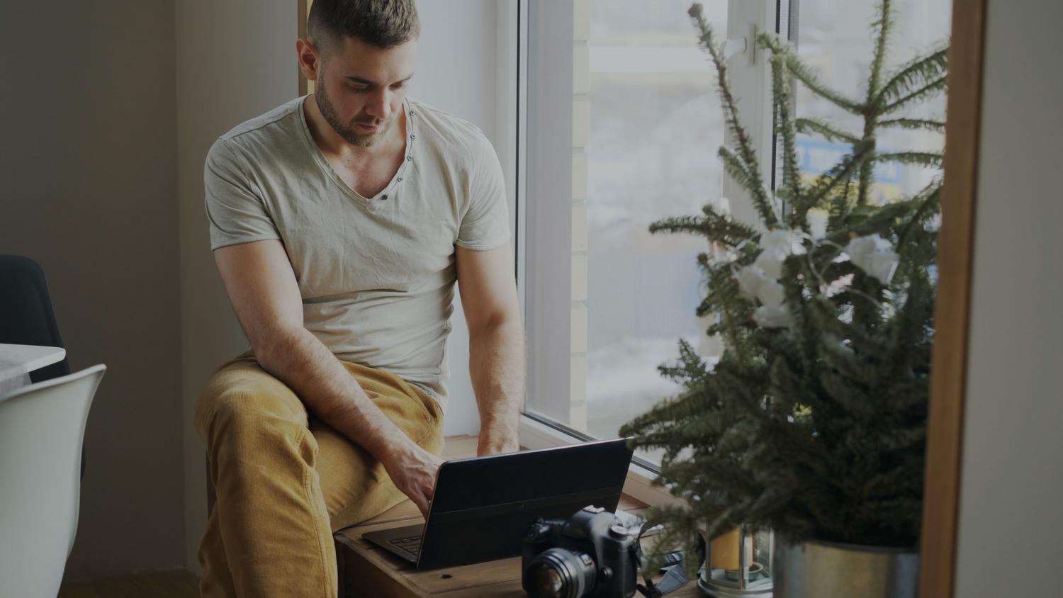 Hombre trabajando con un portátil en una oficina en casa luminosa, representando el estilo de vida del autónomo. Hombre trabajando con un portátil en una oficina en casa luminosa, representando el estilo de vida del autónomo.
