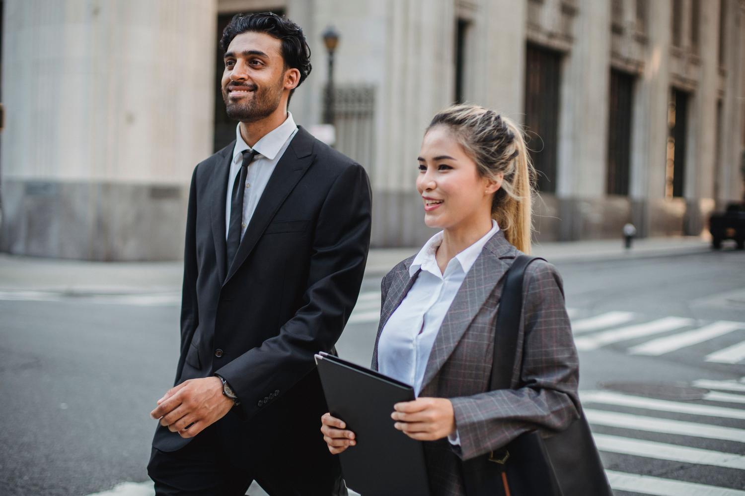 Jóvenes profesionales caminando con confianza por una calle financiera, simbolizando el inicio de una carrera profesional con proyección internacional. Jóvenes profesionales caminando con confianza por una calle financiera, simbolizando el inicio de una carrera profesional con proyección internacional.