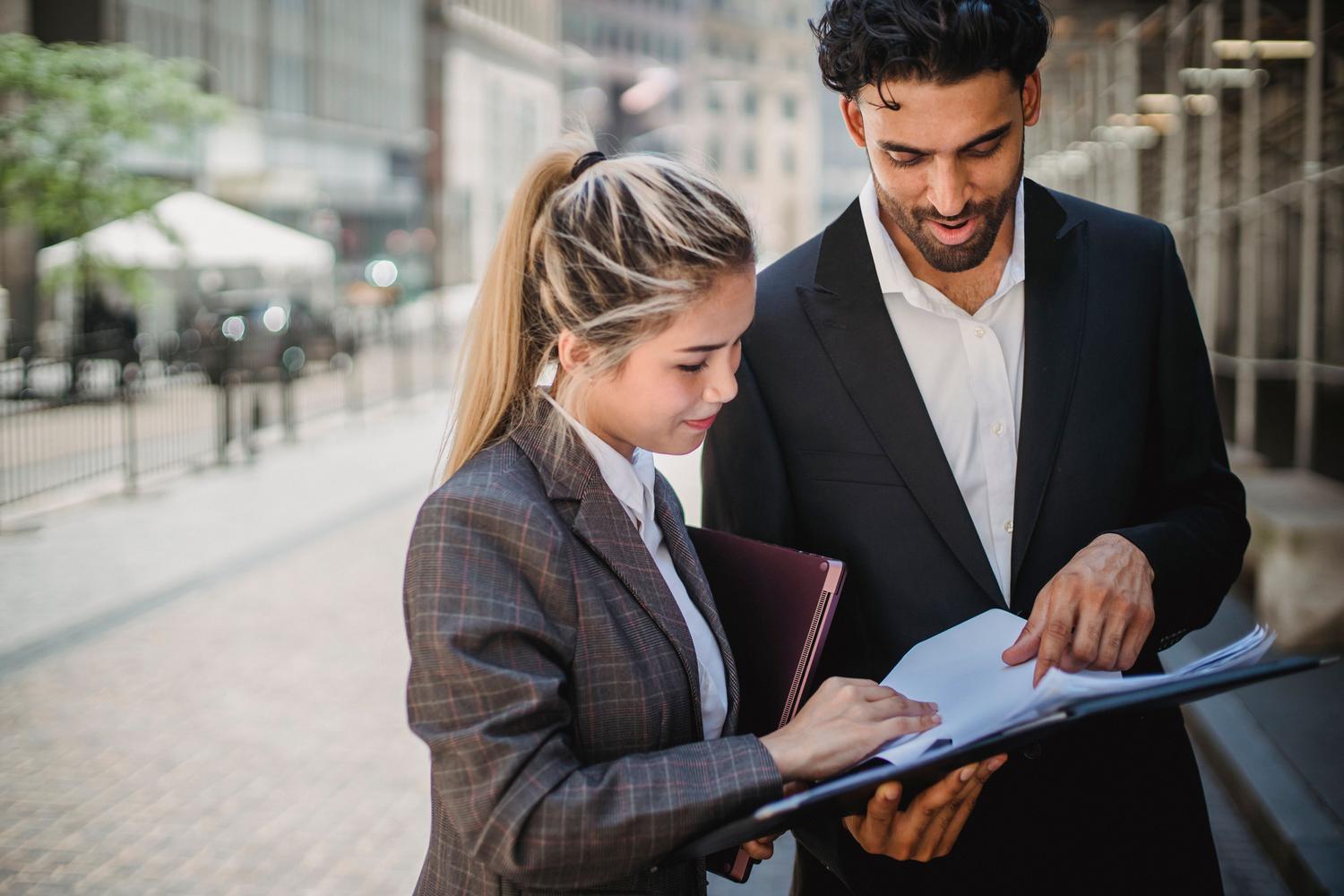 Dos profesionales revisando documentos en un entorno urbano, simbolizando el aprendizaje práctico y los programas de apprenticeships. Dos profesionales revisando documentos en un entorno urbano, simbolizando el aprendizaje práctico y los programas de apprenticeships.