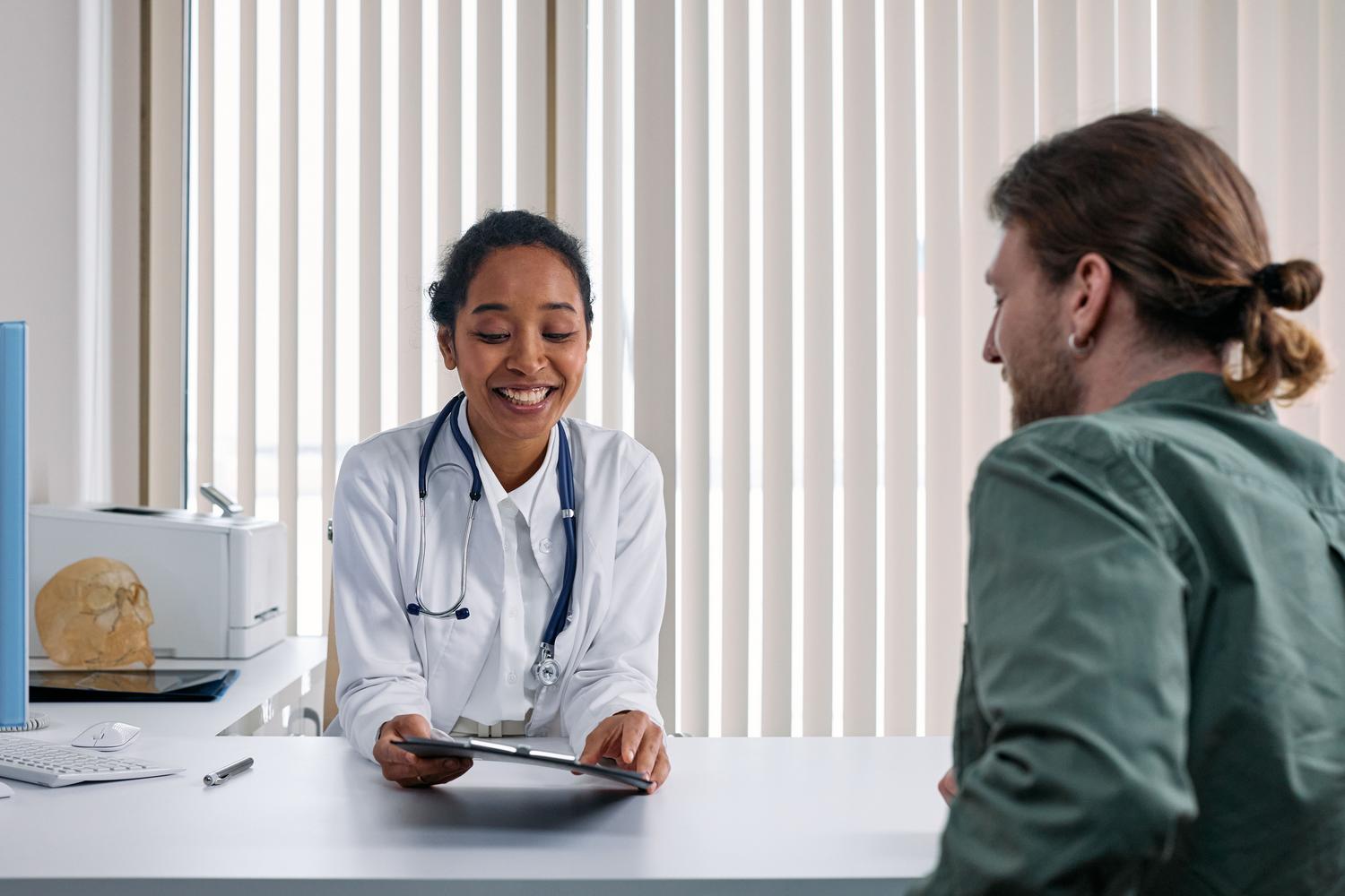 Consulta positiva entre un médico y un paciente en una clínica luminosa, ilustrando la mejora de la relación médico-paciente a través del coaching sanitario. Consulta positiva entre un médico y un paciente en una clínica luminosa, ilustrando la mejora de la relación médico-paciente a través del coaching sanitario.