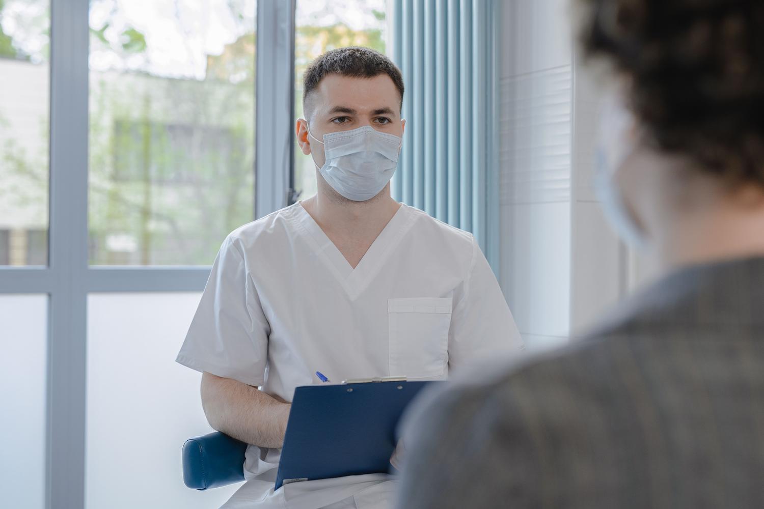 Profesional sanitario consultando con un paciente mientras toma notas, ilustrando el proceso de acompañamiento y las claves técnicas del coaching en salud. Profesional sanitario consultando con un paciente mientras toma notas, ilustrando el proceso de acompañamiento y las claves técnicas del coaching en salud.
