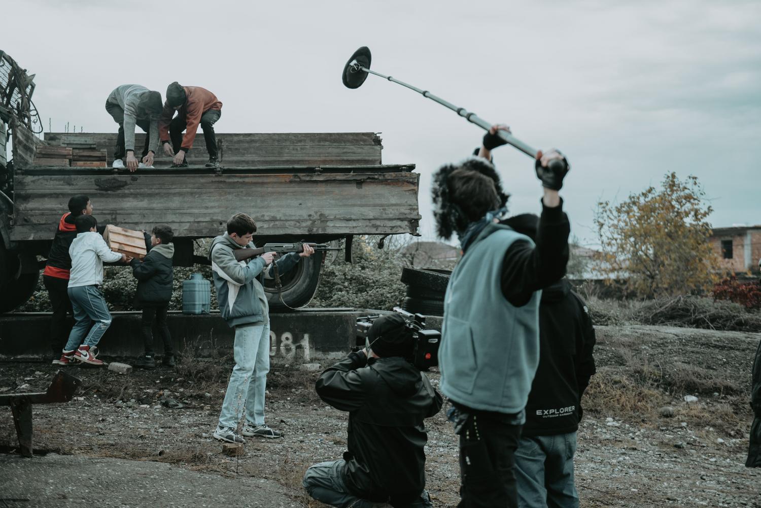 Equipo de rodaje utilizando un micrófono de boom para capturar el audio de una escena en exteriores. Equipo de rodaje utilizando un micrófono de boom para capturar el audio de una escena en exteriores.