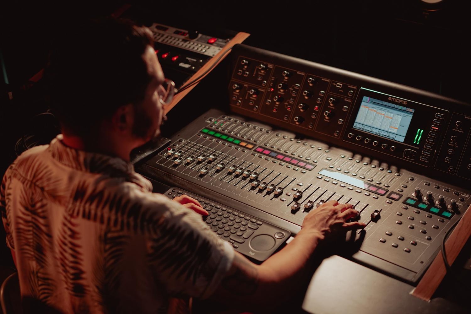 Ingeniero de sonido ajustando los controles de una consola de mezclas profesional en un estudio de grabación. Ingeniero de sonido ajustando los controles de una consola de mezclas profesional en un estudio de grabación.