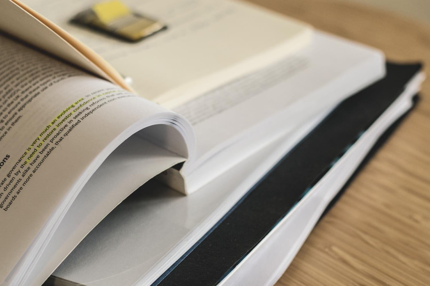 Pila de libros académicos con textos resaltados, simbolizando la producción científica y la cultura del publish or perish. Pila de libros académicos con textos resaltados, simbolizando la producción científica y la cultura del publish or perish.