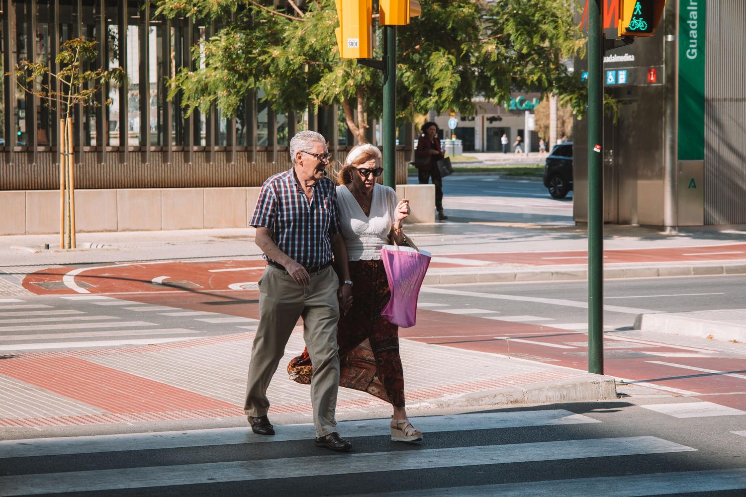 Pareja de personas mayores cruzando una calle soleada en Málaga, España, ilustrando el contexto de la jubilación en el país. Pareja de personas mayores cruzando una calle soleada en Málaga, España, ilustrando el contexto de la jubilación en el país.