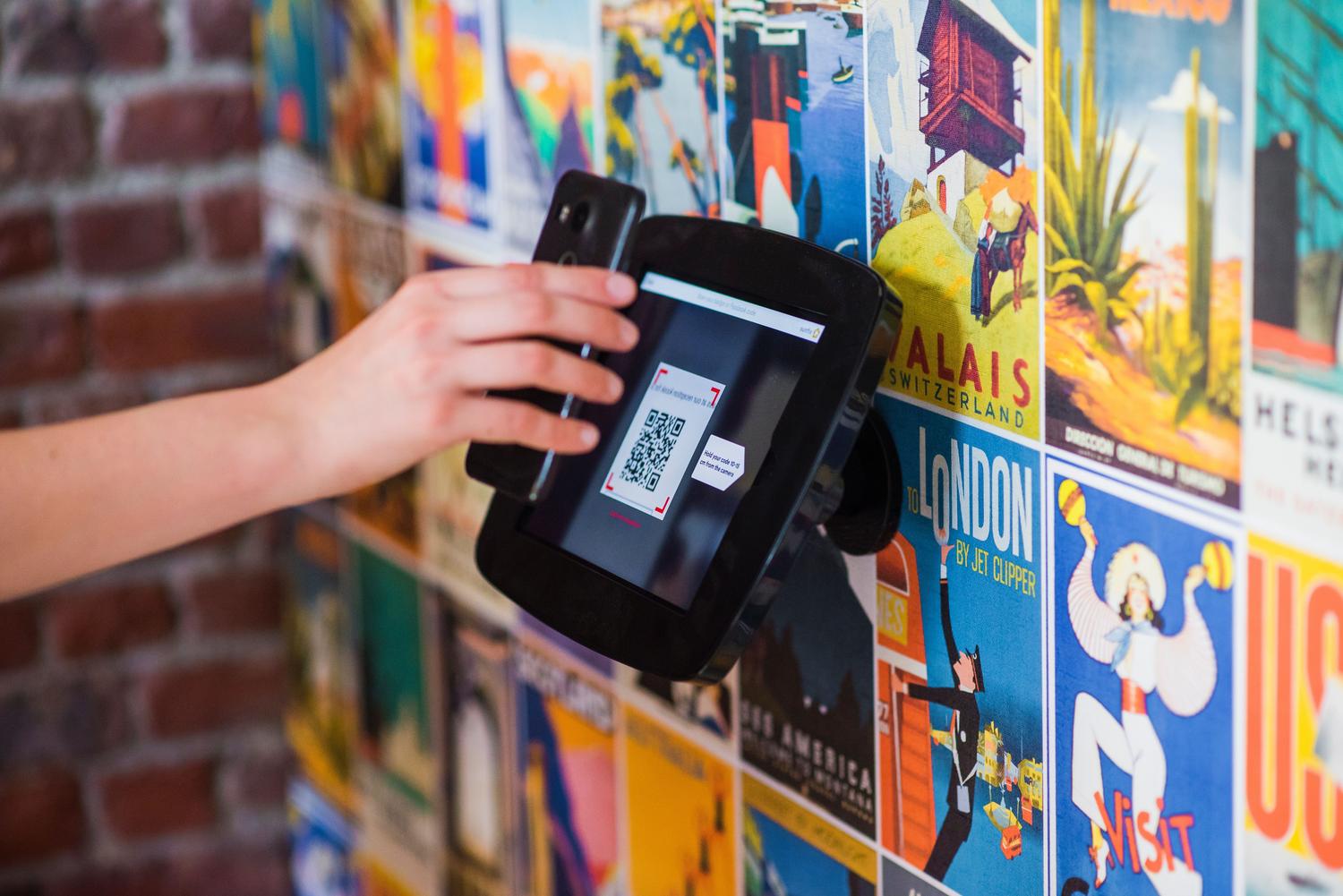 Mano escaneando un código QR en una pantalla instalada en una pared Mano escaneando un código QR en una pantalla instalada en una pared